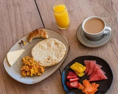 a table with two plates of food and a cup of coffee at Granja del Cafe Hotel y Centro de convenciones in Venecia