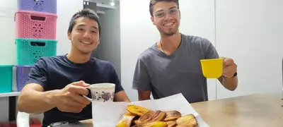 two men sitting at a table with a plate of donuts at Hostel Metro Floresta Alojamiento in Medellín