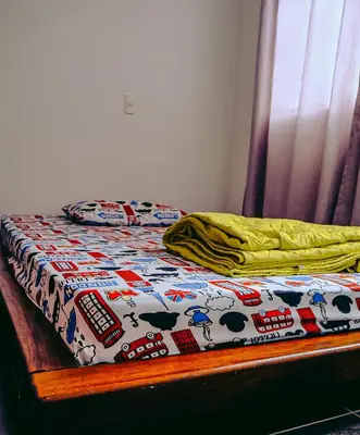 a bed with a comforter with cows on it at Hostel Metro Floresta Alojamiento in Medellín