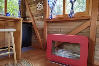 a tiny house with a red fireplace in a room at La Casa En El Bosque in El Retiro