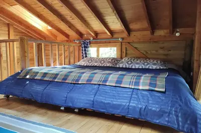 a bed in a cabin with a wooden ceiling at La Casa En El Bosque in El Retiro