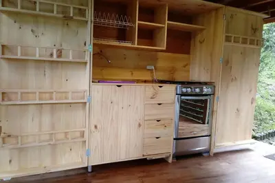 a kitchen with wooden walls and a stove and shelves at La Casa En El Bosque in El Retiro