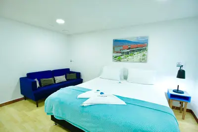 a bedroom with a bed and a blue chair at Poblado Park Guest House in Medellín