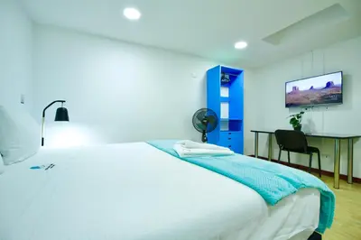a bedroom with a large white bed and a desk at Poblado Park Guest House in Medellín