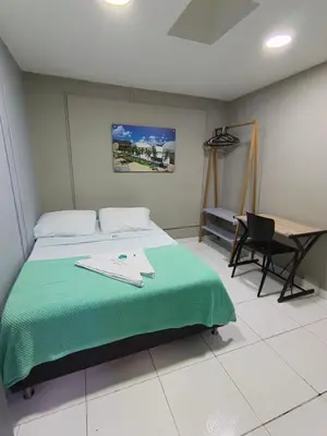a bedroom with a bed with a green blanket and a desk at Poblado Park Guest House in Medellín
