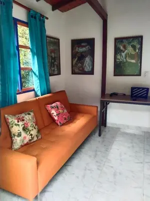 an orange couch in a living room with blue curtains at Génesis, un lugar para descansar y disfrutar in Santa Elena