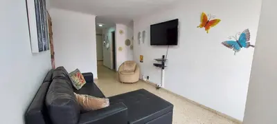 a living room with a couch and a tv on a wall at Amplio Apartamento en Los Colores in Medellín
