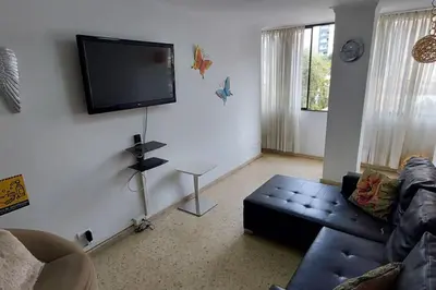a living room with a couch and a flat screen tv at Amplio Apartamento en Los Colores in Medellín