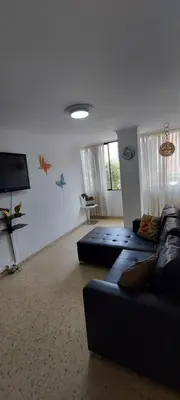 a living room with a couch and a flat screen tv at Amplio Apartamento en Los Colores in Medellín