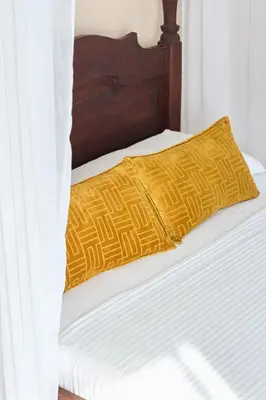 a bed with white sheets and a yellow pillow at Curazao Hotel -Centro Histórico- in Santa Fe de Antioquia