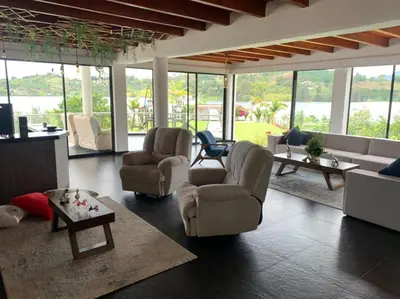 a living room with chairs and tables and windows at Jordan Hotel Boutique in Guatapé