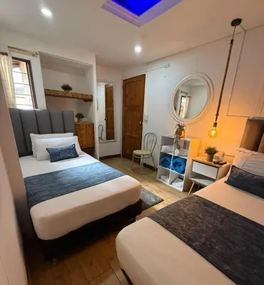 a hotel room with two beds and a mirror at The Garden Lleras 10 in Medellín