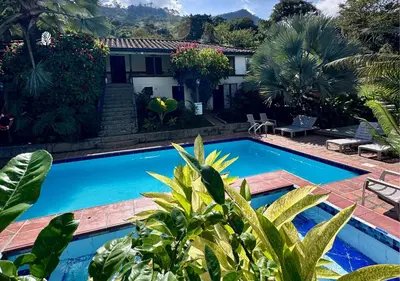 a pool in front of a house with palm trees at All Natural Glamping in Copacabana