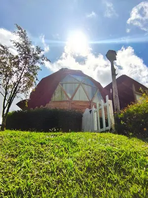 a house with a domed building with the sun behind it at Glamping Cabañas Sharmont in Guarne