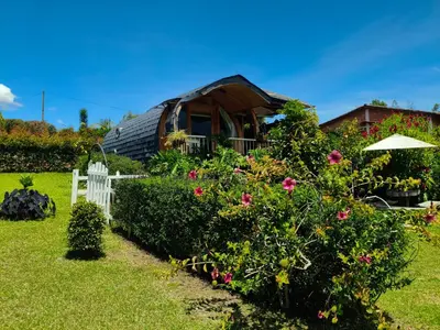 a house with a garden with flowers and a fence at Glamping Cabañas Sharmont in Guarne