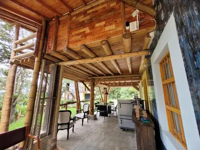 a covered porch with a wooden ceiling and chairs at Refugio en el Bosque in Medellín