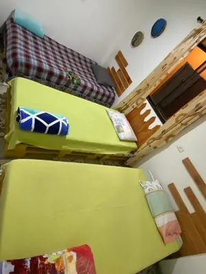 a room with two beds and a green couch at Hotel Hostal El Castillo Santa in Santa Bárbara