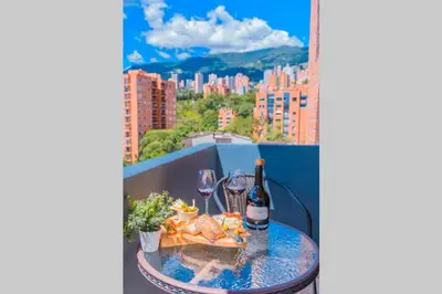 a table with wine glasses and food on a balcony at Beautiful Apartment UltraFast Internet /El Poblado in Medellín