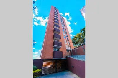 a tall red brick building with a flag on it at Beautiful Apartment UltraFast Internet /El Poblado in Medellín