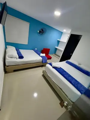 a bedroom with two beds and a blue wall at Hotel Select Medellin in Medellín