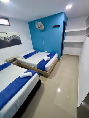 two beds in a room with a blue wall at Hotel Select Medellin in Medellín
