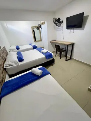 two beds in a room with a desk and a television at Hotel Select Medellin in Medellín