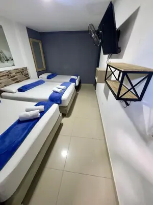 a room with three beds and a flat screen tv at Hotel Select Medellin in Medellín