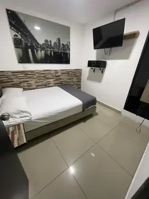a bedroom with a bed and a flat screen tv at Hotel Select Medellin in Medellín