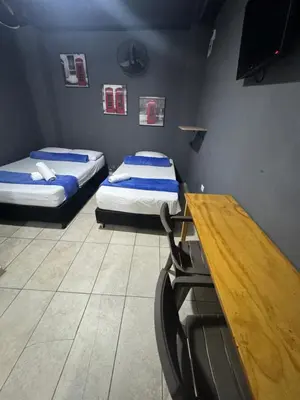 two beds in a room with a desk and a table at Hotel Select Medellin in Medellín
