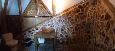 a bathroom with a stone wall with a wooden table at Ecohotel Soplo del Tambo in Cocorná