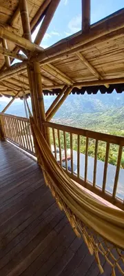 a hammock on a wooden deck with a view at Ecohotel Soplo del Tambo in Cocorná