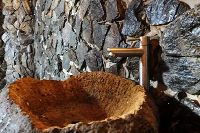 a tree stump with a tap in front of a stone wall at Ecohotel Soplo del Tambo in Cocorná