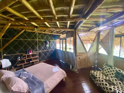 a room with a bed and two chairs in it at Ecohotel Soplo del Tambo in Cocorná