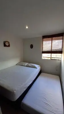 two beds in a small room with two windows at Apartamento en Calasanz con piscina y parqueadero in Medellín