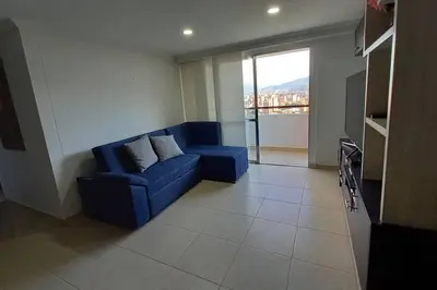 a living room with a blue couch and a window at Apartamento en Calasanz con piscina y parqueadero in Medellín