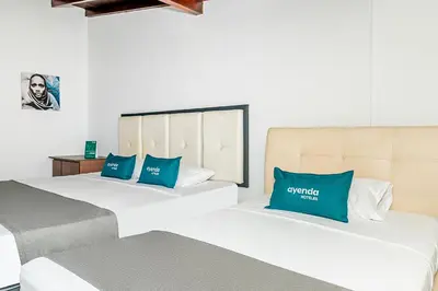 two beds in a hotel room with blue pillows at Ayenda Casa San Pablo in Medellín