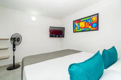 a bedroom with a bed with blue pillows and a tv at Ayenda Casa San Pablo in Medellín