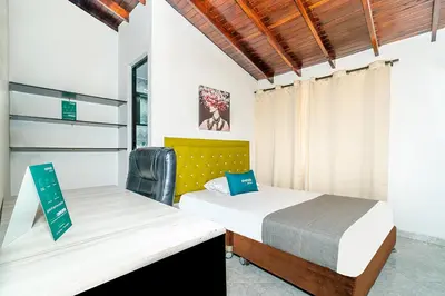 a bedroom with two beds and a chair at Ayenda Casa San Pablo in Medellín