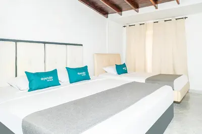 two beds in a hotel room with blue pillows at Ayenda Casa San Pablo in Medellín