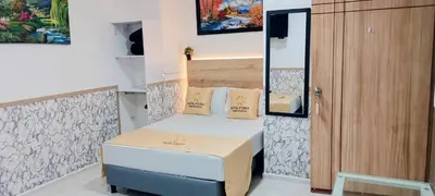 a small room with a bed and a wooden cabinet at Hotel Eterna Primavera in Medellín