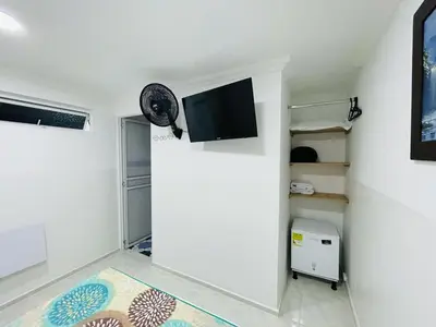 a room with a white wall with a flat screen tv at Hotel Eterna Primavera in Medellín