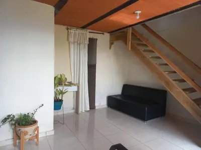 a living room with a couch and a staircase at Cabaña Noche De Luna in Jardin