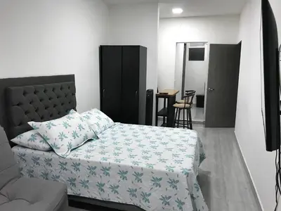 a bedroom with a bed and a chair and a table at Aparta estudio amoblado Medellin, San joaquin in Medellín