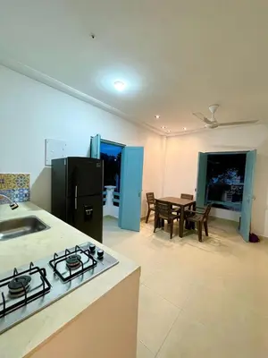 a kitchen with a black refrigerator and a table at Cabaña Villa Jardín - Aldea Doradal - Santorini Colombiano in Doradal