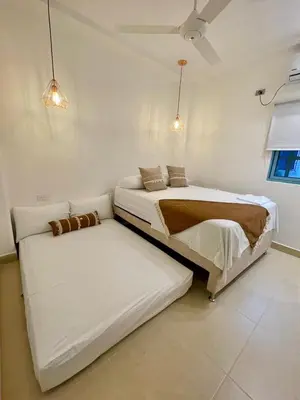 two beds in a room with white walls at Cabaña Villa Jardín - Aldea Doradal - Santorini Colombiano in Doradal