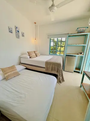 two twin beds in a room with a window at Cabaña Villa Jardín - Aldea Doradal - Santorini Colombiano in Doradal