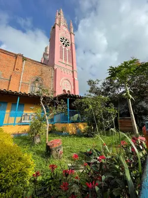 a church with a clock tower in a yard at Parcerito's Hostel in Jericó