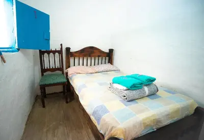 a small bedroom with a bed and a chair at Parcerito's Hostel in Jericó