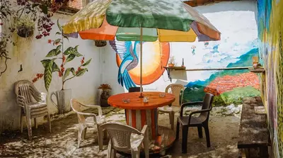 a table with an umbrella in a room with a mural at Parcerito's Hostel in Jericó