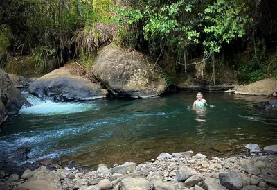 a woman is swimming in a river near rocks at Parcerito's Hostel in Jericó